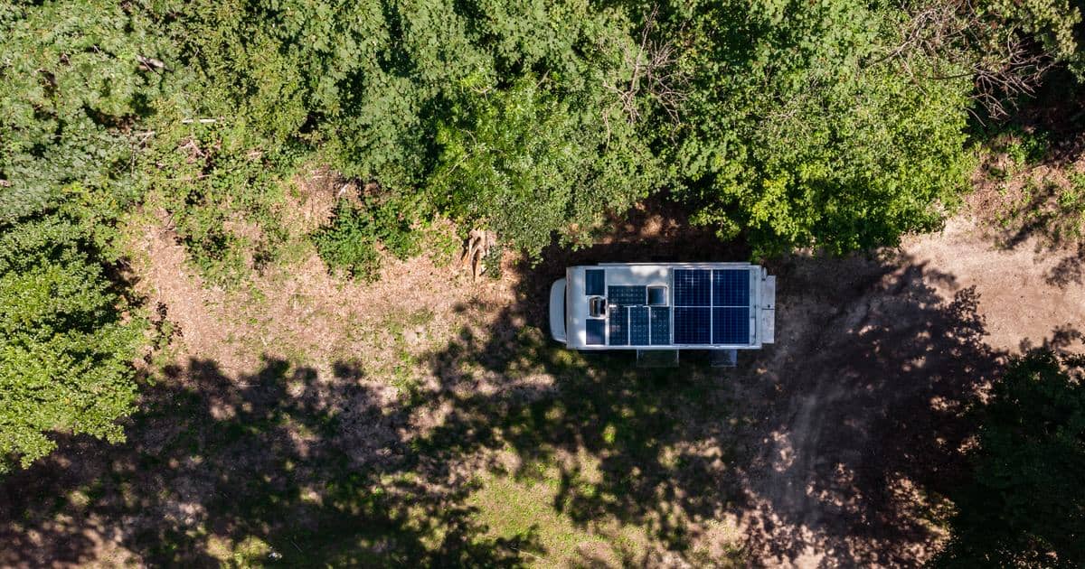 Luftaufnahme eines Wohnmobils mit Solaranlage auf dem Dach, geparkt auf einer Waldlichtung